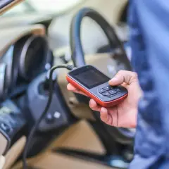 Diagnostyka Renault: ręka trzyma czytnik OBD, który może wykryć błąd DTC B1267.