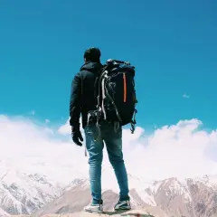 Un uomo con zaino in spalla ammira un panorama montano innevato. Il viaggiare da soli psicologia è un'esperienza di crescita.
