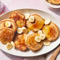 Tortitas de avena y plátano doradas, cubiertas con rodajas de plátano y sirope. Un desayuno delicioso y saludable.