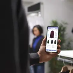 Mężczyzna przegląda trendy ecommerce na telefonie, wybierając koszulę w sklepie.
