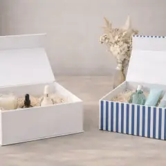 Zwei offene Geschenkboxen, eine weiße mit Pflegeprodukten, eine gestreifte mit Parfum und Cremes. Perfekt zum geschenkbox basteln.