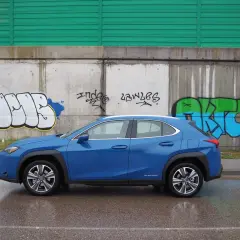 Lexus UX azul aparcado frente a un muro con grafitis. A pesar de los problemas, el coche eléctrico se ve elegante.