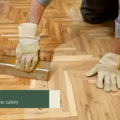 Ręce w rękawiczkach pracują nad odnawianiem drewnianej posadzki parkietowej.