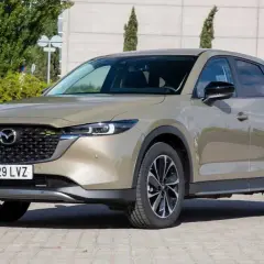 Un Mazda CX-5 2.2 150cv color bronce, con llantas negras y plateadas, estacionado en un día soleado. ¡Un coche ideal para tus viajes!