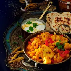 Aksamitne curry z kalafiora z mleczkiem kokosowym, podane z chlebkami naan i jogurtem.