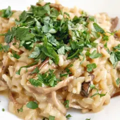 Kremowe risotto z grzybami, posypane świeżą natką pietruszki. Idealne na jesienny obiad.