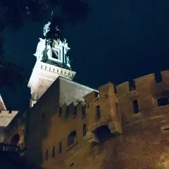 Wieczorne ciekawostki o Krakowie: Wawel nocą, z murami i wieżą oświetloną blaskiem księżyca.