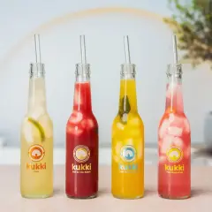 Vier bunte Kukki Cocktails mit Eis und Strohhalmen, bereit zum Auftauen und Genießen.