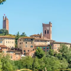Borgo medievale di San Miniato con torri imponenti e case in pietra, immerso nel verde della campagna toscana.