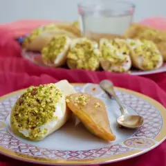 Atayef recept: söta pannkakor fyllda med grädde och pistagenötter, serverade på en tallrik med en sked.