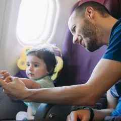 Tata bawi dziecko paluszkową zabawką, jednym z gadżetów do samolotu dla dzieci.