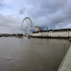 Widok na Tamizę z charakterystycznym London Eye w tle, pod pochmurnym niebem.