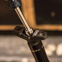 A socket wrench tightens a bolt on a Reverb Stealth dropper post.