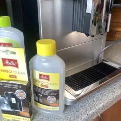Płyn i tabletki Melitta Perfect Clean obok ekspresu. Idealne, by dowiedzieć się, jak odkamienić ekspres Dolce Gusto.