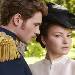 Młody mężczyzna w mundurze i kobieta w kapeluszu, przypominający obsadę filmu o cesarzowej Sisi, patrzą w różne strony.