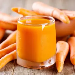Succo d'arancia brillante circondato da carote fresche, un concentrato di vitamine e benefici per la salute.