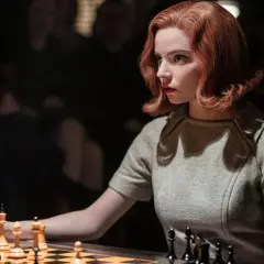 Beth Harmon, bohaterka "Gambitu królowej 2", skupiona nad szachownicą, przygotowuje się do kolejnego ruchu.