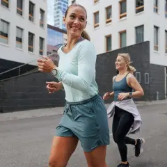 Dwie kobiety biegają po mieście, przygotowując się do treningu ultramaraton 50 km. Uśmiechnięte, pełne energii.