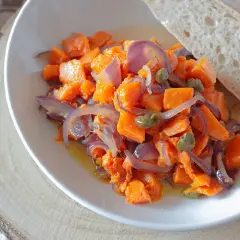 Zucca in padella con cipolle rosse e capperi, un contorno saporito servito con pane fresco.