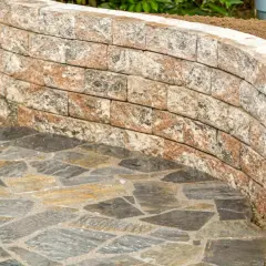 Muretto curvo in pietra per giardino, con pavimentazione irregolare in ardesia. Belle idee per muretti da giardino.