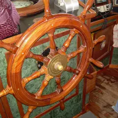 Il timone, come si chiama il volante della nave, è di legno lucido, pronto a guidare.