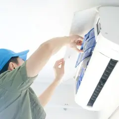 Un technicien nettoie le filtre d'une climatisation, une obligation pour le bailleur afin d'assurer le confort et la qualité de l'air.