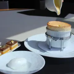 Un délicieux soufflé au Grand Marnier, encore chaud, est servi avec une crème anglaise. À côté, des petits gâteaux au chocolat et une boule de sorbet.