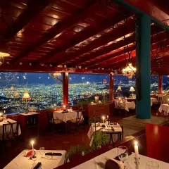 Mesas puestas con velas y vistas a la ciudad iluminada. Un lugar perfecto para saber donde cenar en San José.