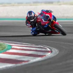 Motocyklista pochyla się na zakręcie, polegając na kontroli trakcji, by utrzymać przyczepność.
