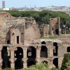 Antiche rovine del **Monte Palatino a Roma**, con archi imponenti e mura di mattoni che si stagliano contro il cielo azzurro.
