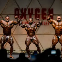 Drei Bodybuilder präsentieren ihre Muskeln auf der Bühne des Mr. Olympia Open.
