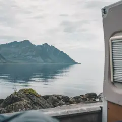 Widok z kampera na spokojne morze i góry w Norwegii. Idealne miejsce na podróż kamperem.