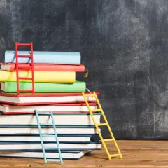 Stos kolorowych książek z drabinkami, symbolizujący drogę do wiedzy. Idealny do nauki anatomia funkcjonalna dla fizjoterapeutów.