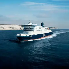 Duży prom DFDS płynie po wzburzonym morzu w kierunku białych klifów. To widok na trasie do Dunkierki.