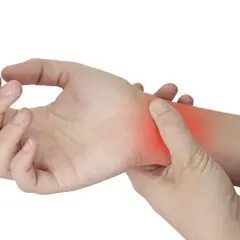 Una mano se presiona la muñeca, donde un área roja indica dolor por tendinitis.