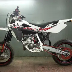 Husqvarna SMS 125 w białej odsłonie z czerwono-czarnymi grafikami, gotowy do jazdy po mieście i torze.