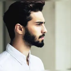 Profil d'un homme avec une barbe haute sur les joues, portant une chemise blanche.
