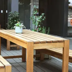 Ensemble de mobilier d'extérieur en bois, table et bancs, dont le traitement met en valeur la beauté naturelle du bois.