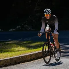 Kolarz na podjeździe. Podczas jazdy na rowerze pracują mięśnie nóg, pośladków i brzucha.