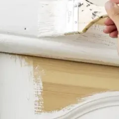 Application de peinture blanche sur un meuble en bois, montrant qu'il est possible de peindre métal sans décaper.