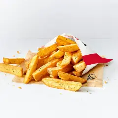 Stos małych frytek z KFC wysypany z papierowej torebki na białym tle.