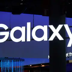 Jasne, oto tekst alternatywny:

Duży, biały napis "Galaxy" na niebieskim tle. Pod nim mniejszy napis "et things done". W tle widać elementy wystroju, w tym niebieskie światła. To wszystko nawiązuje do technologii i innowacji, które chroni **Knox**.