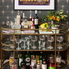 A stylish bar cart with bottles, glassware, lemons, and kumquats, offering inspiration on how to style a bar cart for a sophisticated home bar.