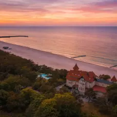 Zachód słońca nad Bałtykiem, malowniczy dworek i plaża. Idealne miejsce na wakacje w Polsce.