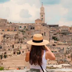 A woman in a straw hat takes in the ancient city of Matera, a highlight of any southern Italy trip itinerary.