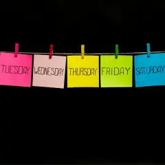 Post-it colorati con i giorni della settimana appesi a un filo. Il giovedì in inglese, "Thursday", è su un foglio giallo.