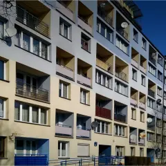 Blok mieszkalny z balkonami i antenami satelitarnymi. Idealne miejsce, gdzie szukać tanich mieszkań, jeśli cenisz sobie widok na miasto.