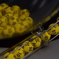 Żółte kulki z numerami w maszynie losującej, które wyłonią zwycięzców gry Eurojackpot.