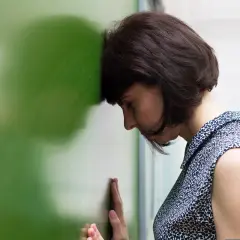 Kobieta z głową opartą o zieloną tablicę, przeżywająca objawy zazdrości i zawiści jako główny konflikt w relacjach literackich.