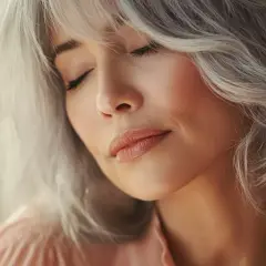 Mujer con un corte wolf cut moderno y cabello plateado, con los ojos cerrados y una expresión serena.